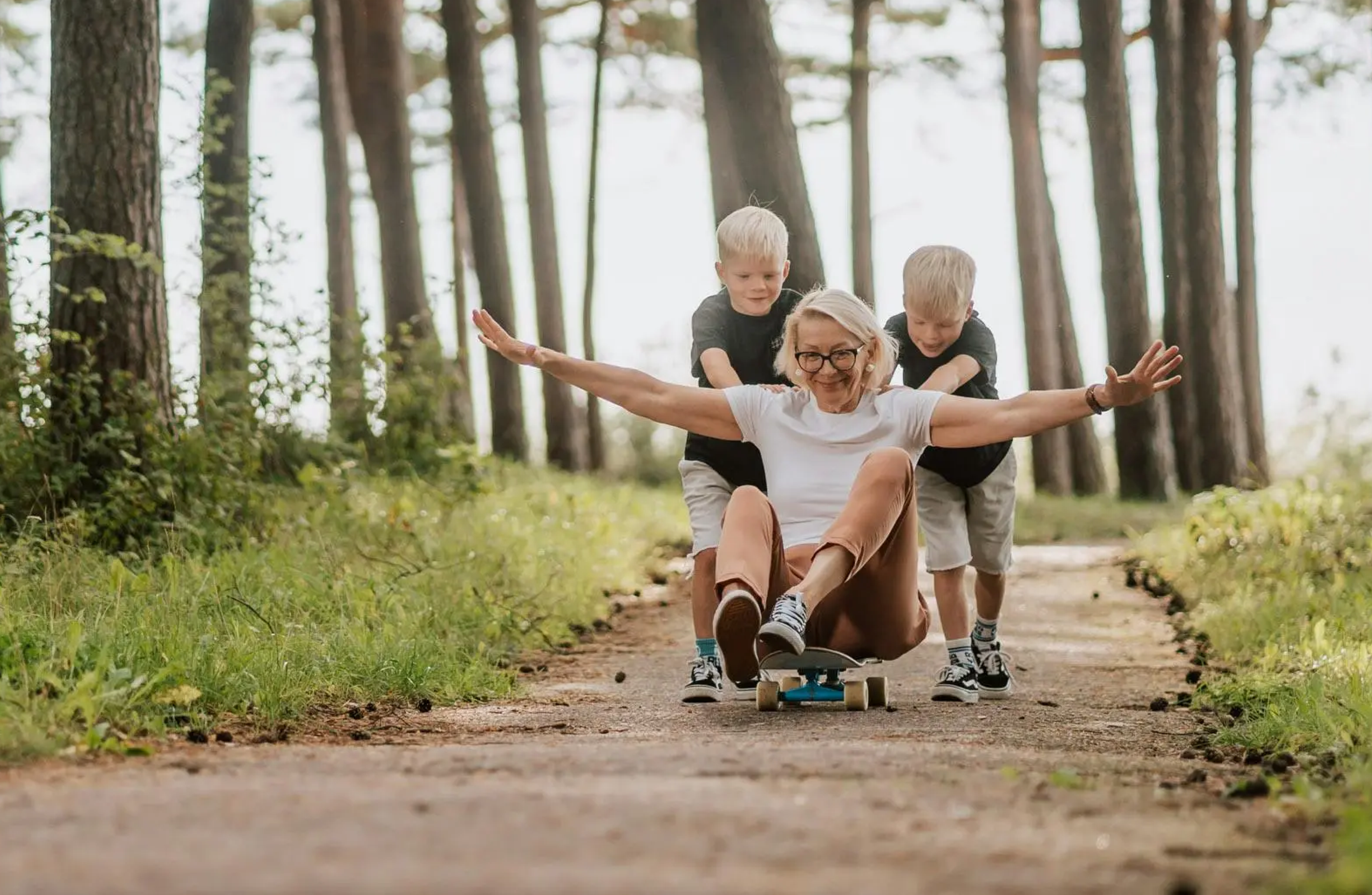 Meliva brand photography — a woman on a longboard with two children in a forest