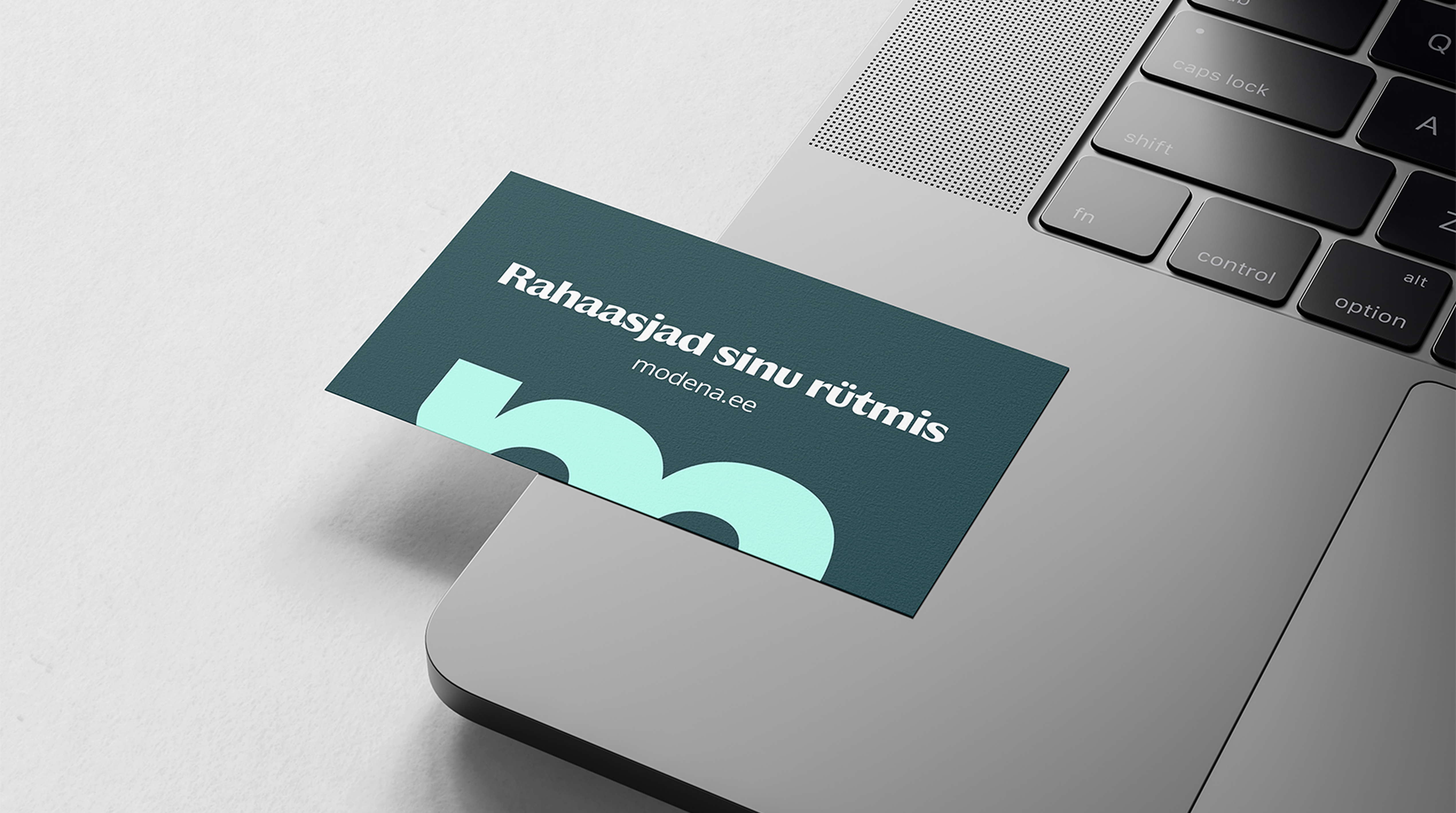 Modena business card resting on a laptop, reading 'Finances in your rhythm'
