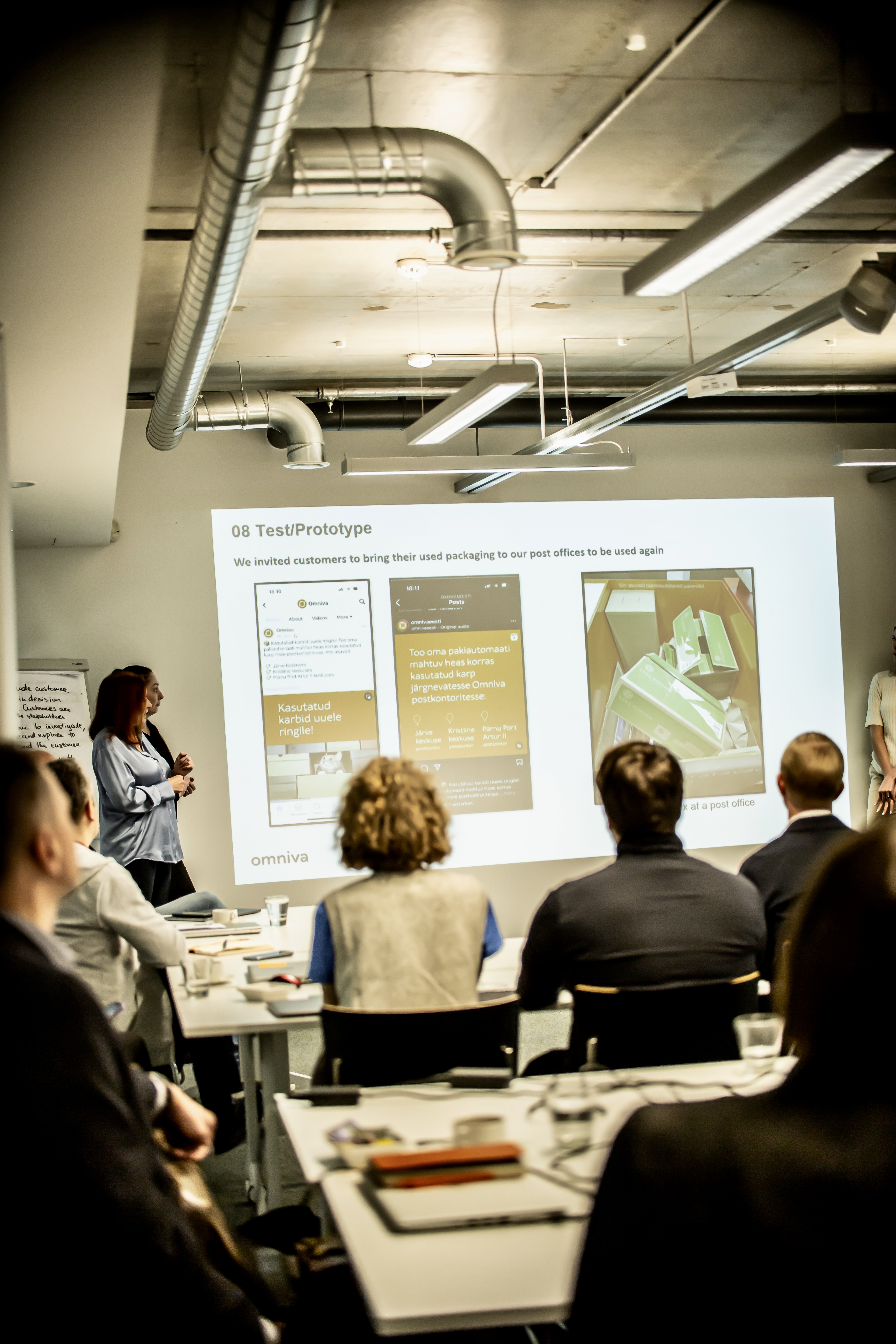 A facilitator presenting a prototype slide about reusing Omniva packaging