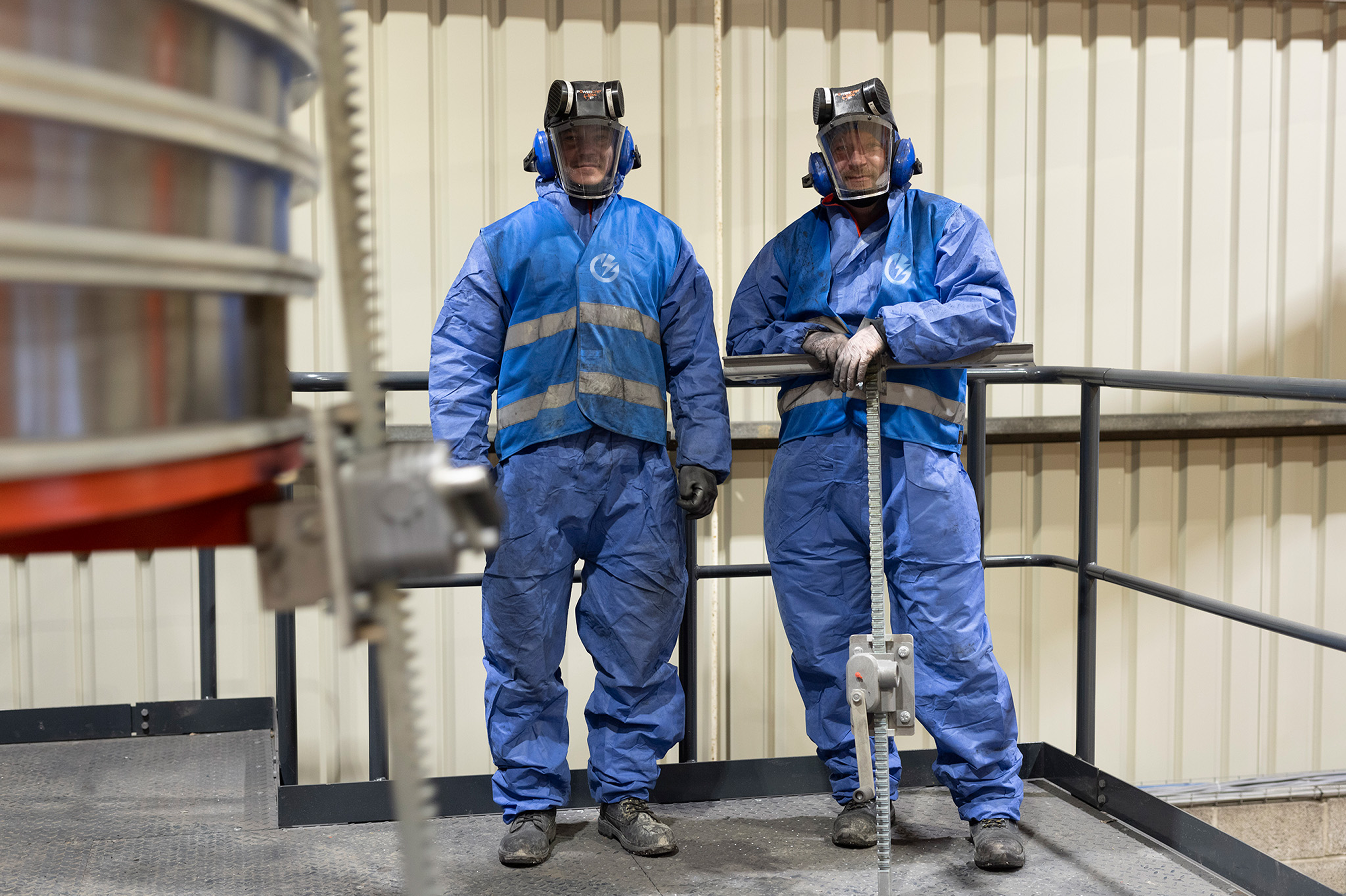 Two workers in Storm Energia protective gear at the battery recycling facility