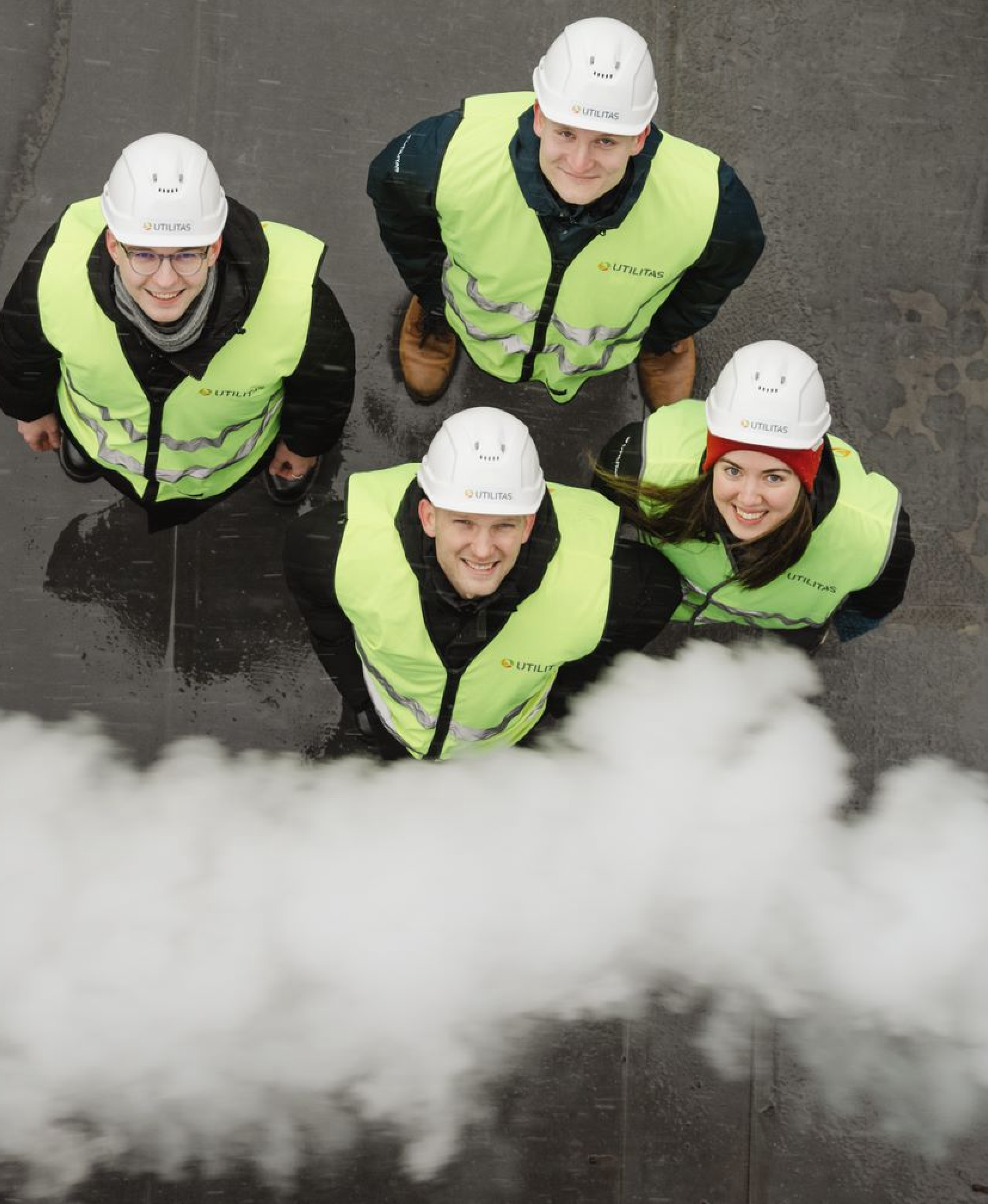 Four Utilitas workers in hi-vis gear photographed from above near rising steam